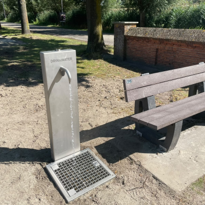 Watertappunt met een bankje ernaast in een groen perkje